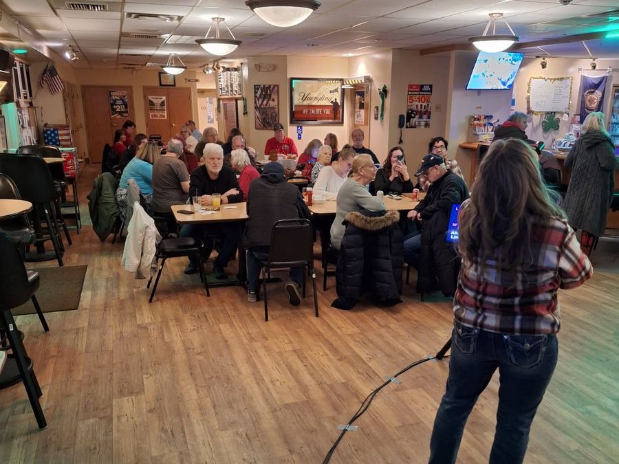 A singer at the mic in front of a full room at a BillyO karaoke show